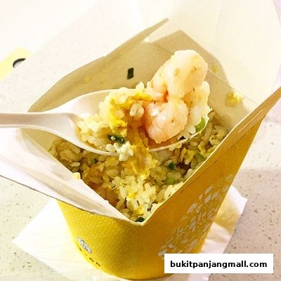 A close-up shot of a spoonful of shrimp fried rice being lifted from a yellow takeout container.