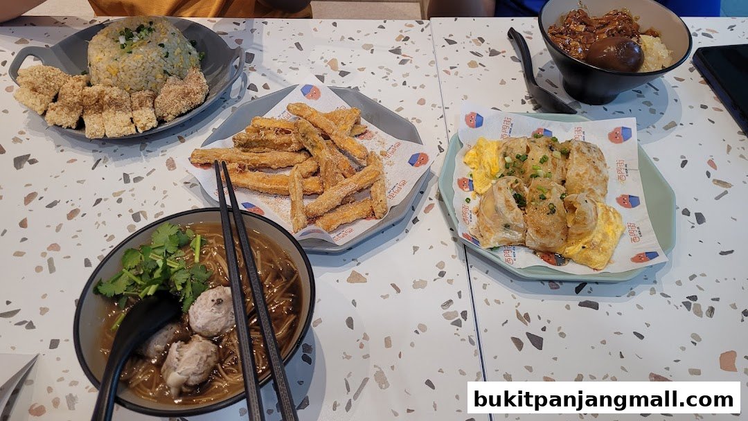 A table laden with various Taiwanese dishes, including fried chicken, fried sweet potato, and a noodle soup.