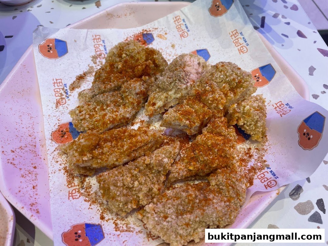 A plate of Taiwanese fried chicken, seasoned with chili powder, served on branded paper.