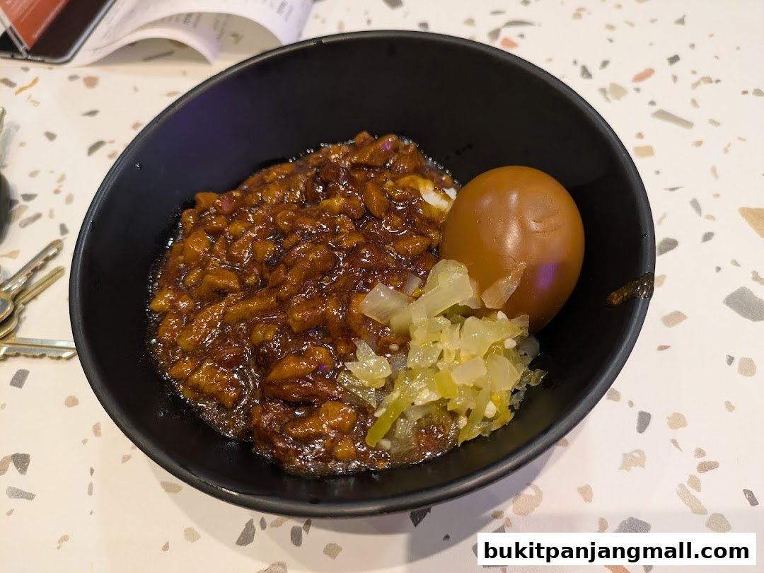 A bowl of Taiwanese braised pork rice with a braised egg and pickled vegetables.