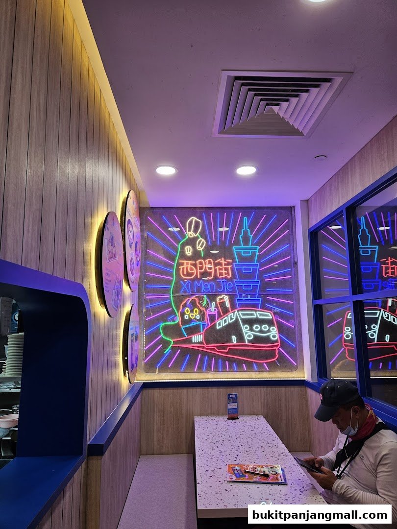 Interior of a Taiwanese restaurant with neon signs and a customer at a table.
