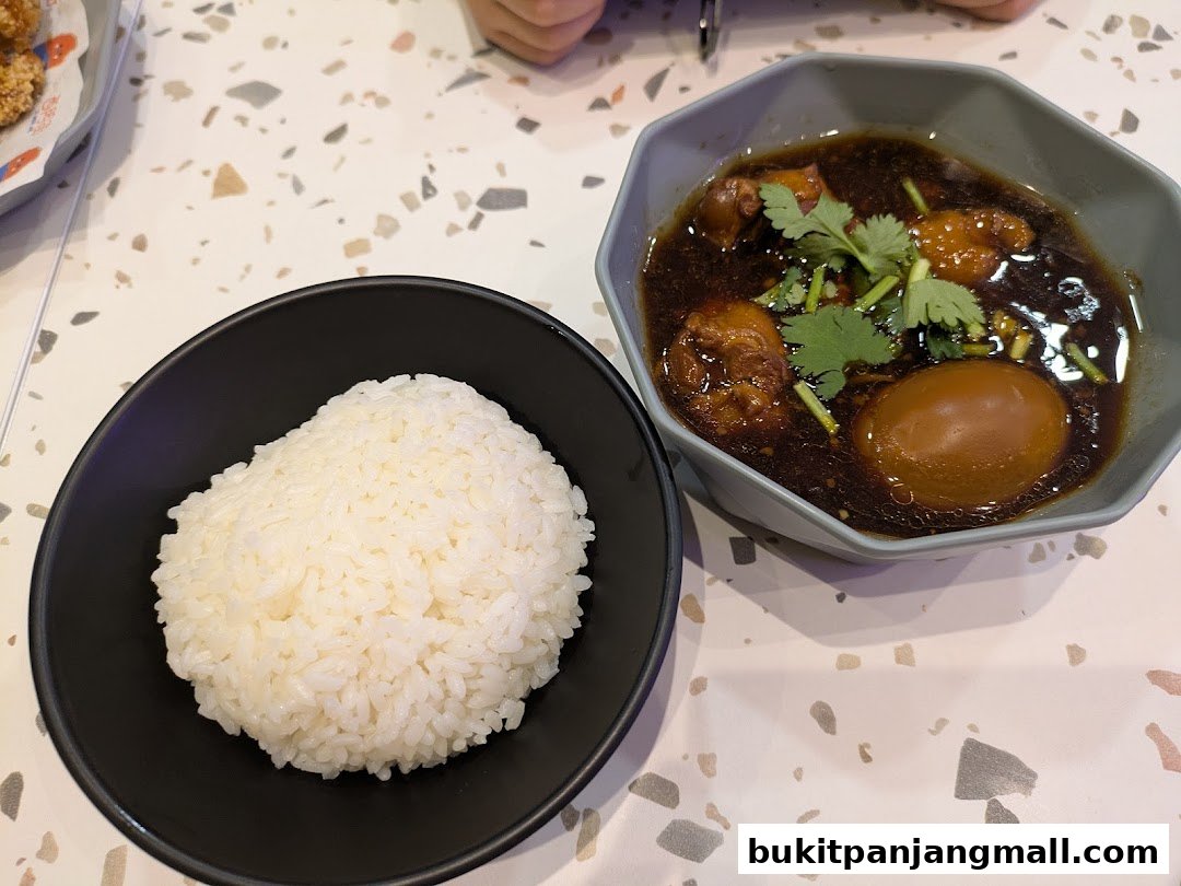 A bowl of white rice next to a bowl of braised meat and egg in dark sauce.