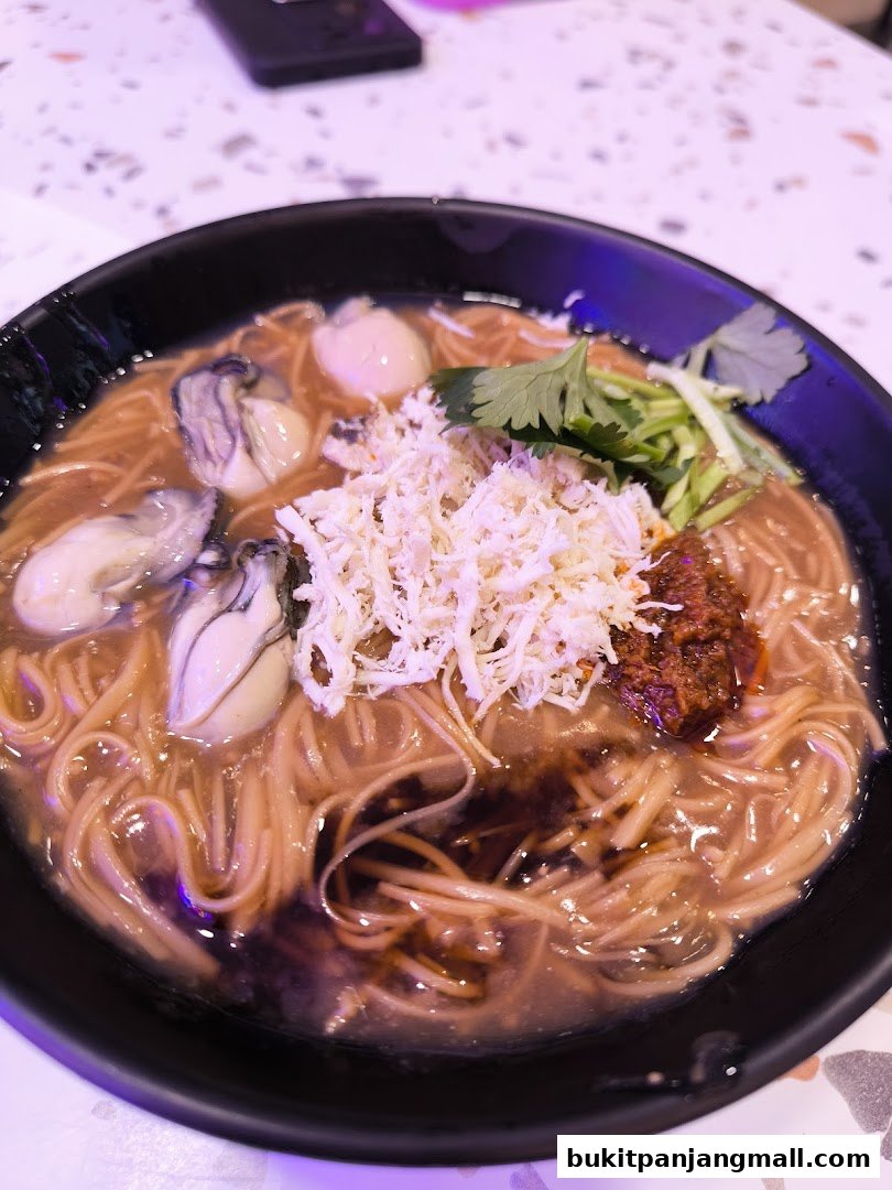 A close-up shot of a steaming bowl of oyster mee sua with shredded chicken and chili paste.