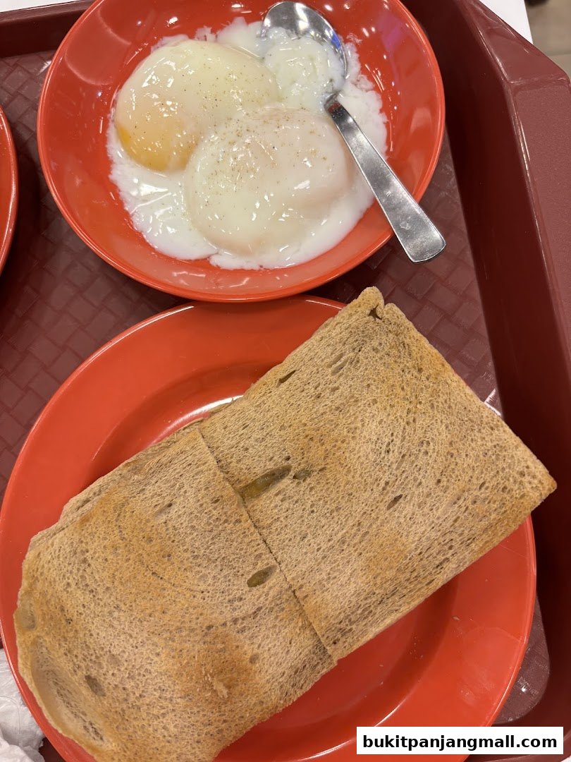 A close-up shot of soft-boiled eggs and kaya toast served on red plates.