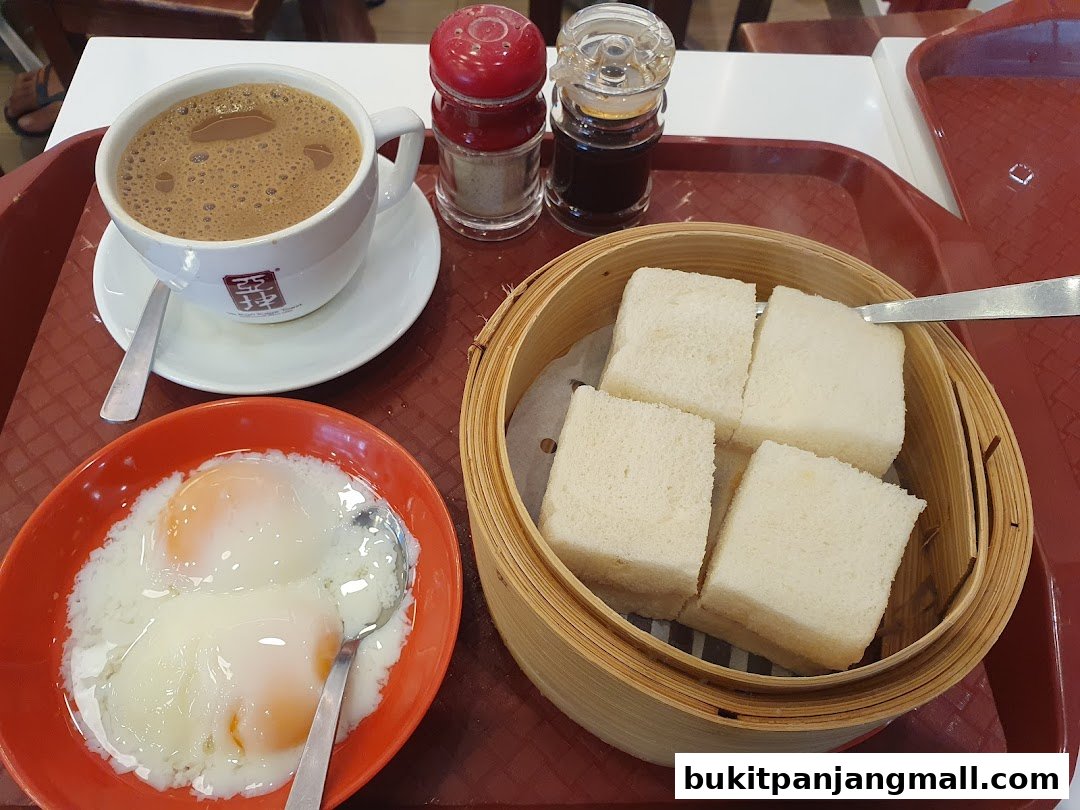 A tray with a cup of coffee, soft-boiled eggs, and steamed bread slices.