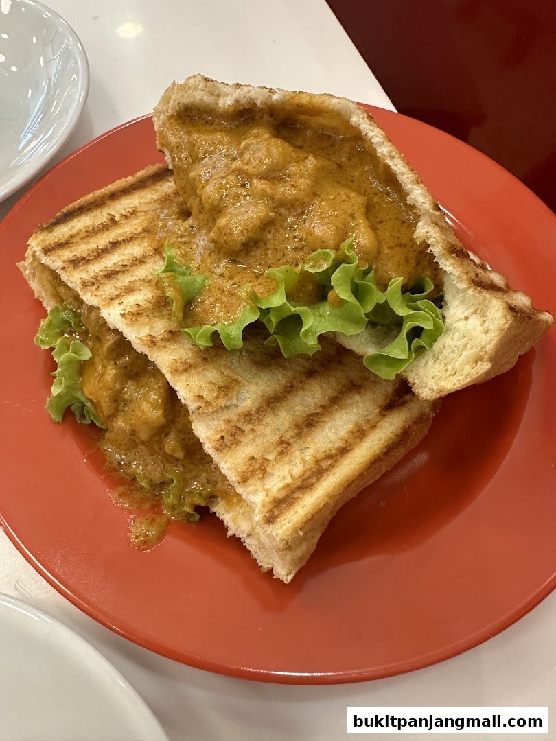 A close-up shot of a grilled sandwich filled with curry and lettuce on a red plate.