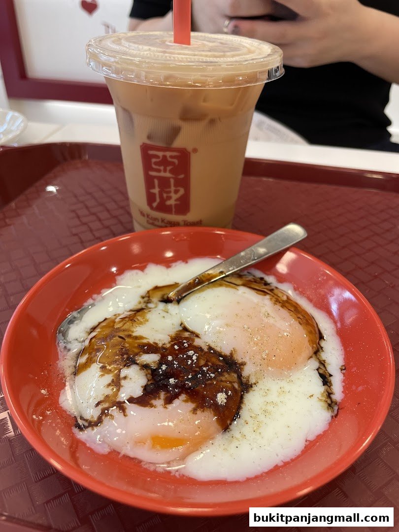 A close-up of soft-boiled eggs with soy sauce and pepper, next to an iced milk tea.