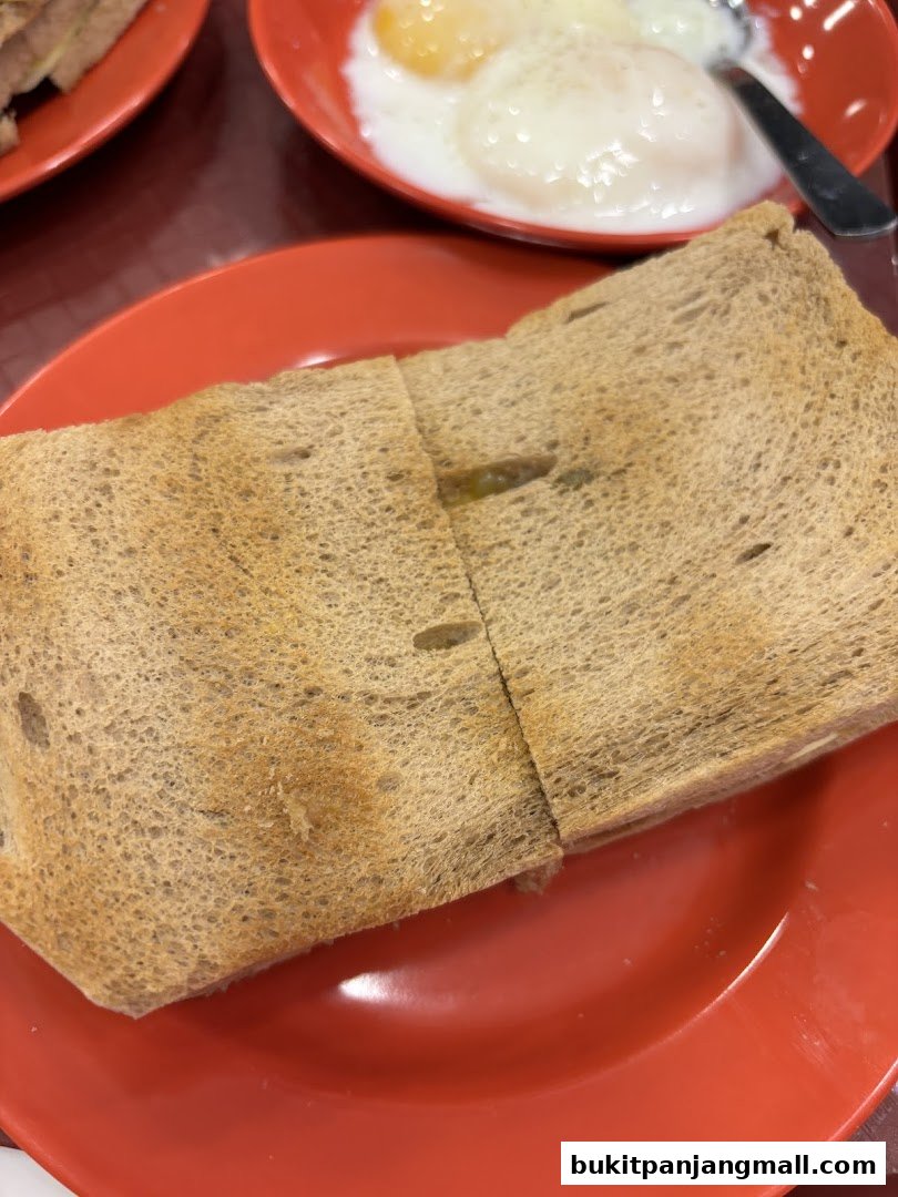 A close-up shot of kaya toast and soft-boiled eggs on red plates.