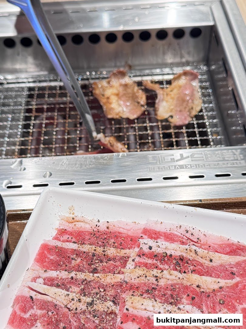 Slices of raw beef seasoned with pepper are ready to be grilled on a barbecue.