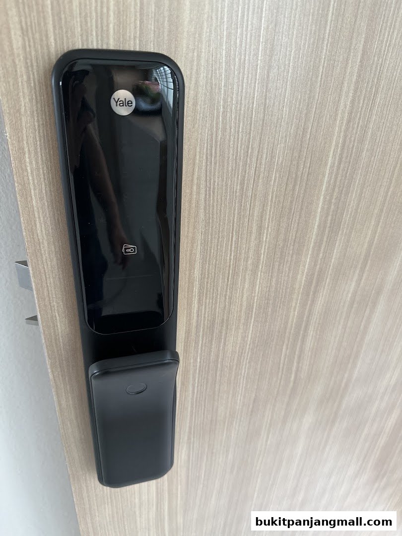 A close-up of a black Yale smart lock installed on a light wood door.