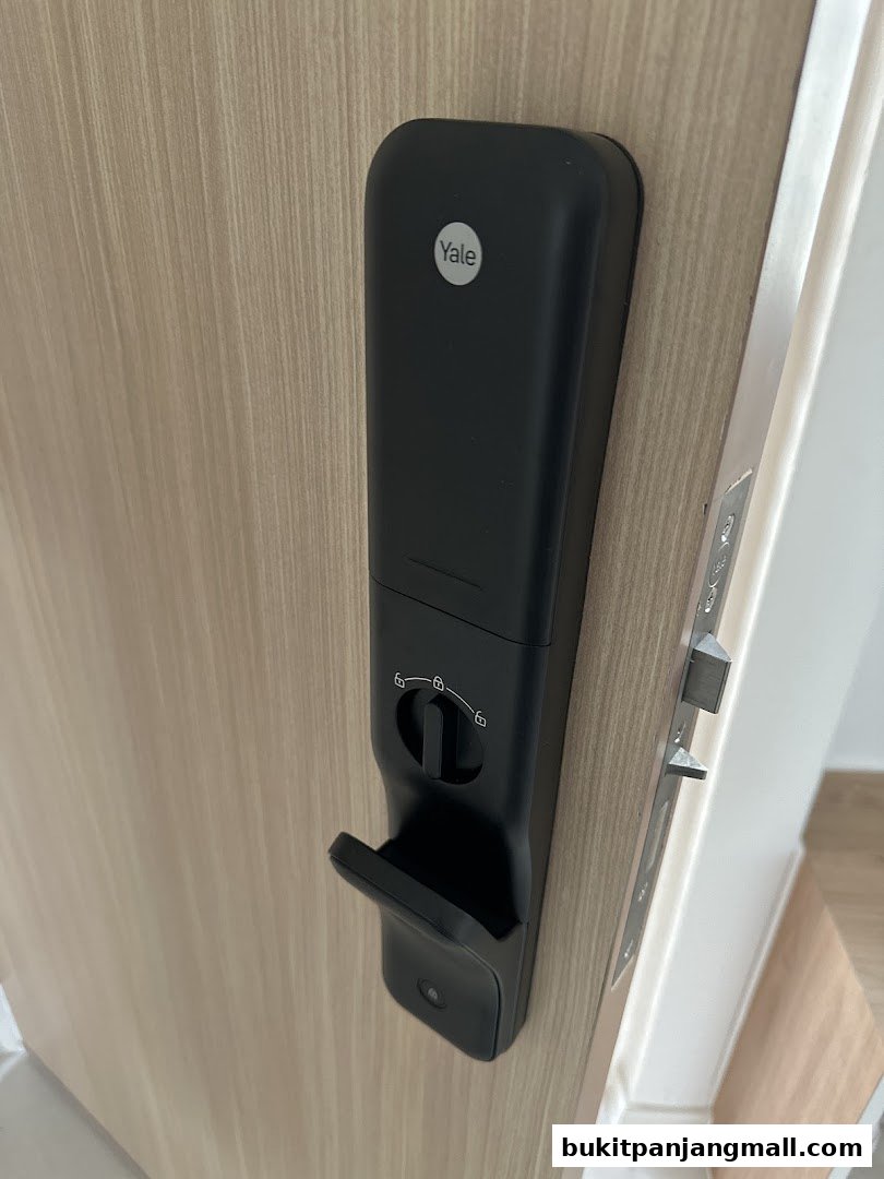 A close-up view of a black Yale smart lock installed on a light wood door.
