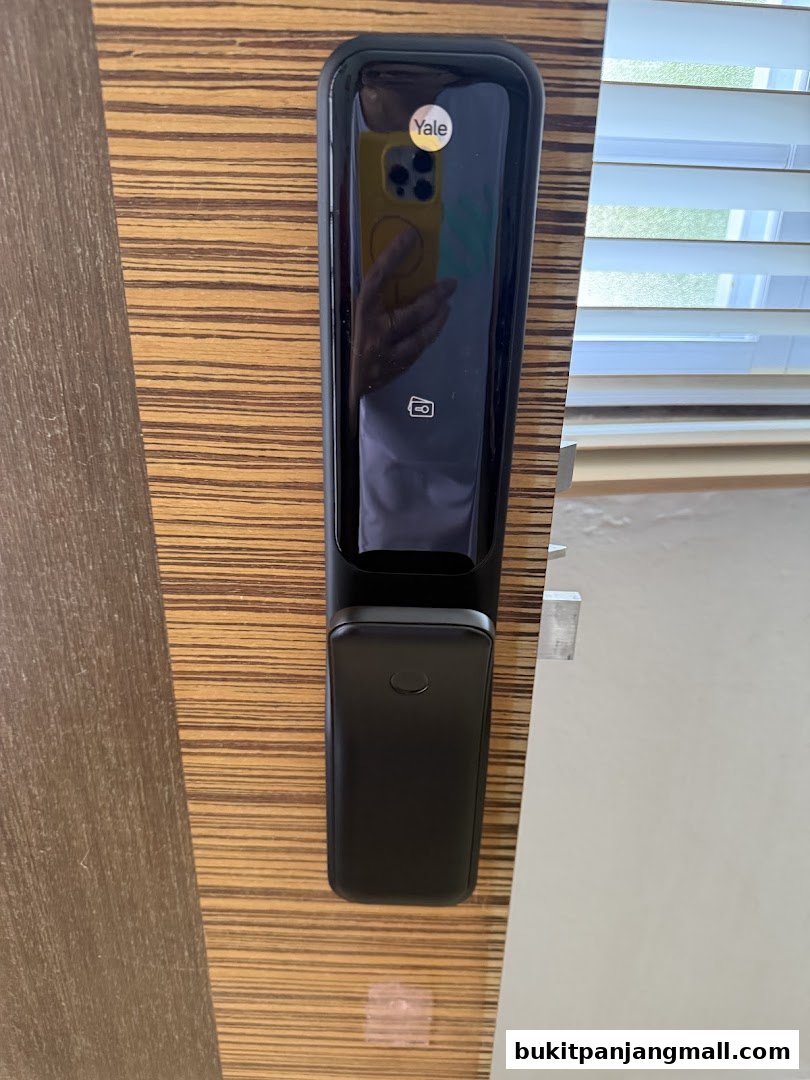 A close-up of a Yale smart lock installed on a wooden door.