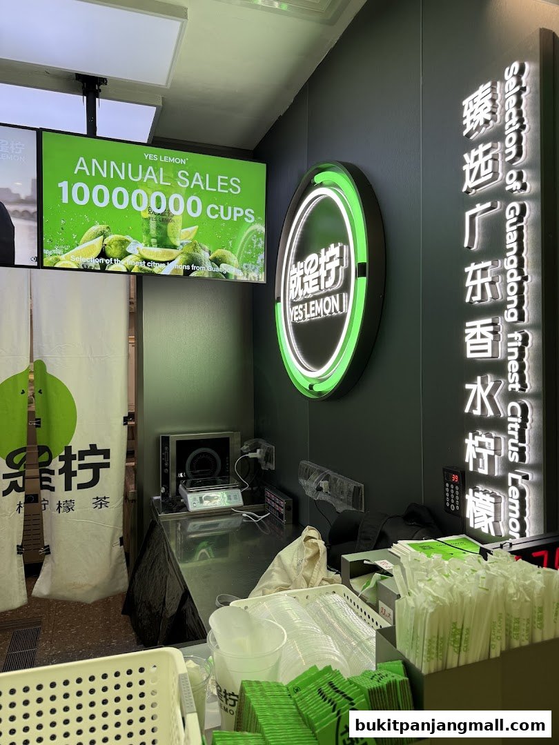 A beverage shop counter with branding, cups, straws, and a digital display.