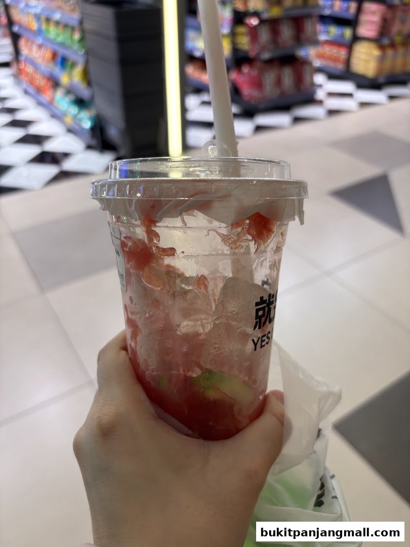 A hand holds a nearly empty cup of iced strawberry and avocado drink from YES LEMON BPP.