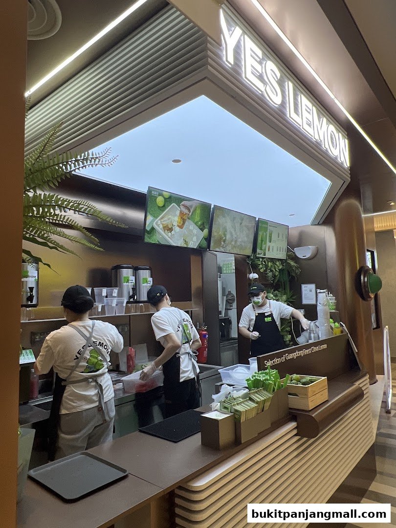 Staff preparing drinks at the YES LEMON BPP counter with digital menu screens.