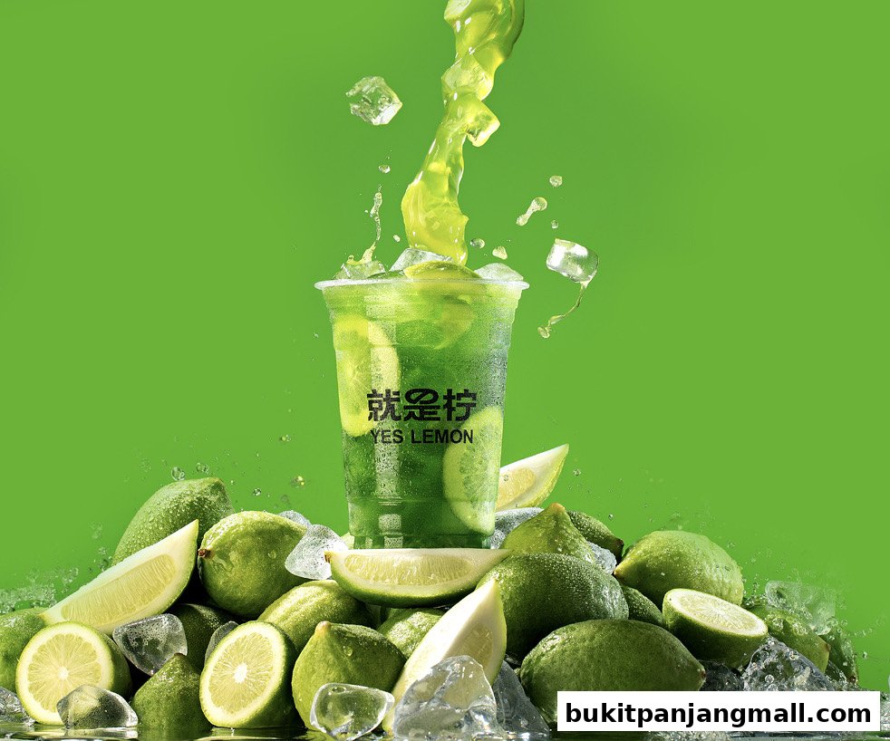A refreshing green drink with lemons and ice, splashing in a cup.
