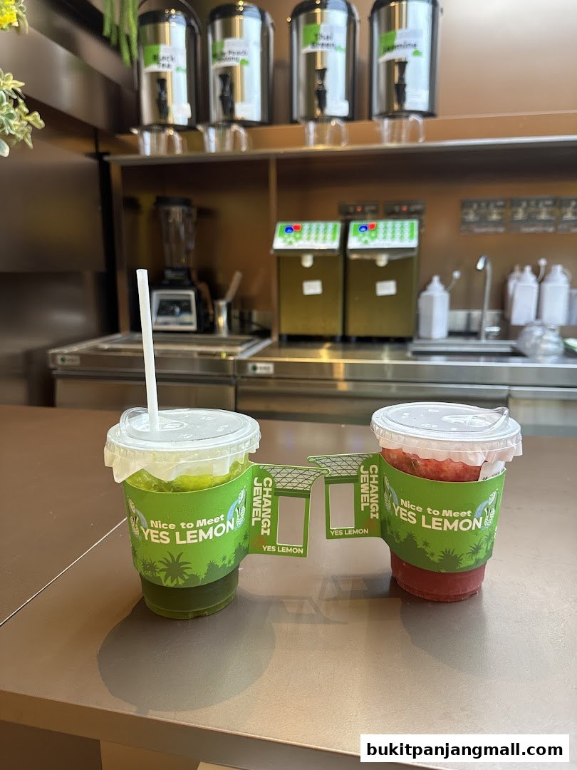 Two refreshing drinks from YES LEMON, one green and one red, displayed on a counter.