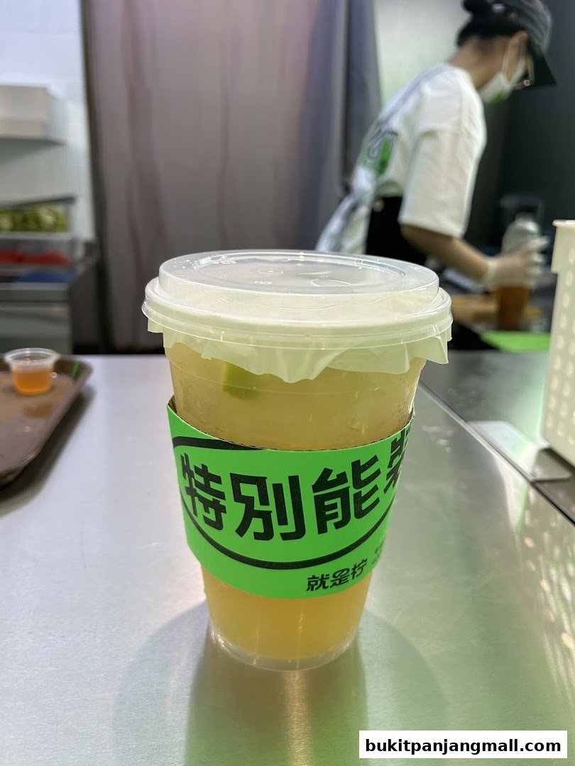 A refreshing drink with a green sleeve featuring Chinese characters, served in a clear plastic cup.