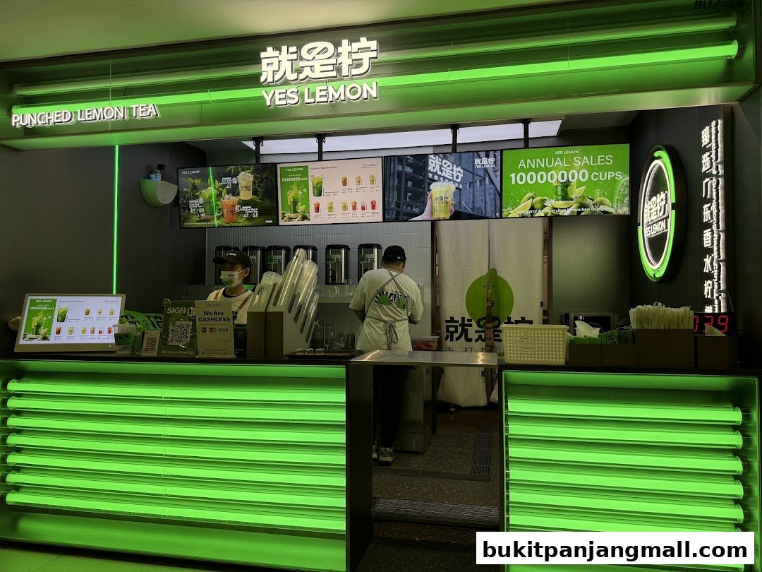 A brightly lit "YES LEMON" shop counter with staff preparing drinks and promotional displays.