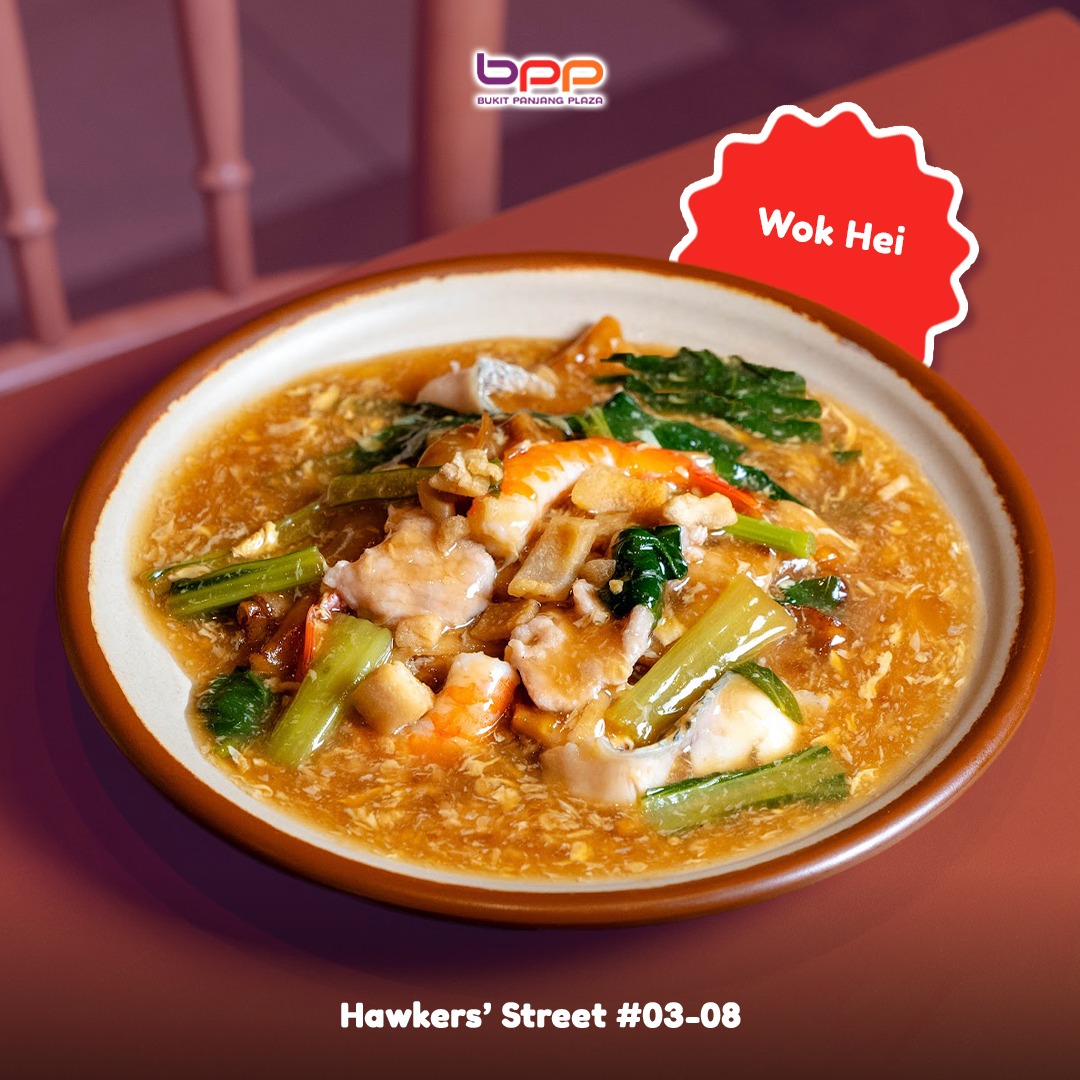 A sizzling stir-fried dish, possibly noodles or rice, showcasing the smoky char of 'wok hei'.